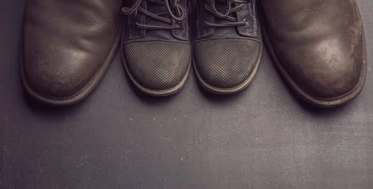 Worn shoes side by side on a dark floor