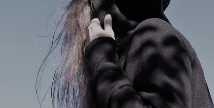 A person with long hair in a black hoodie, face hidden