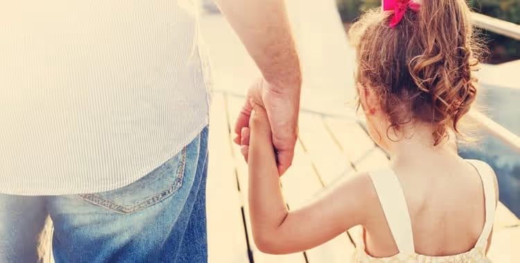 A father holding his young daughter’s hand